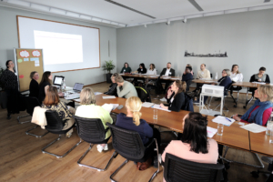 Workshopteilnehmer*innen sitzen in einem Seminarraum. Die Tische sind U-förmig gerstellt