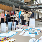 Besucher*innen stehen in Gruppen oder allein an Infoständen der Messe