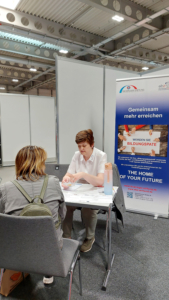 BLEIBdran plus-Mitarbeiterin berät eine Interessierte am EBZ Messestand